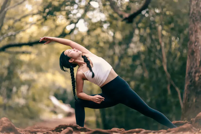 A woman practicing yoga outdoors in warm natural light
