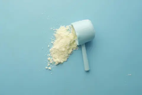 White amino acid powder in a scoop on a blue background representing glycine supplementation