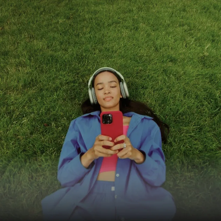 A Mito member relaxing outdoors on the grass, checking their results on their phone