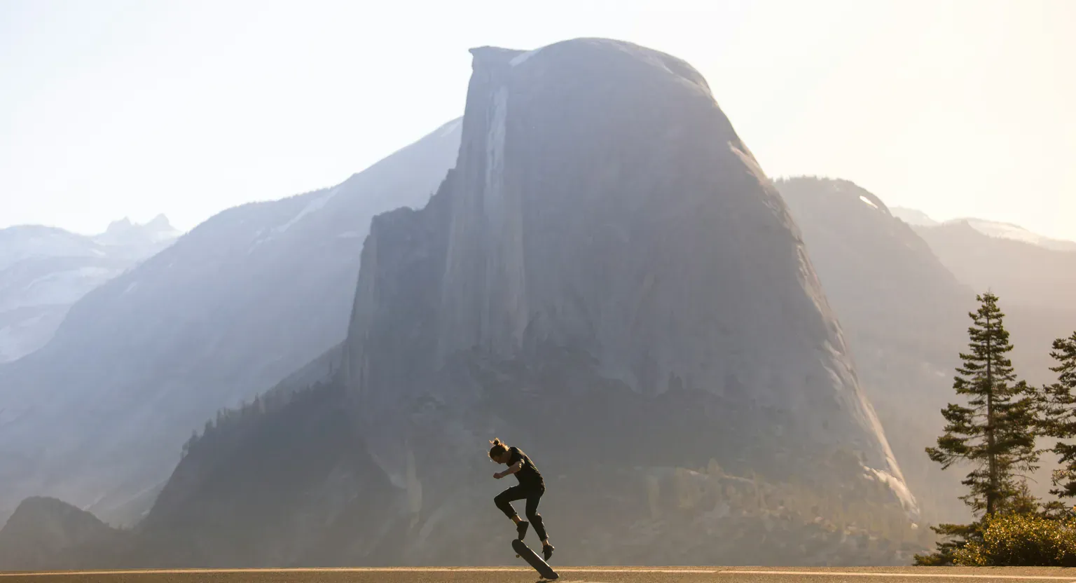 A runner on a road below a granite mountain