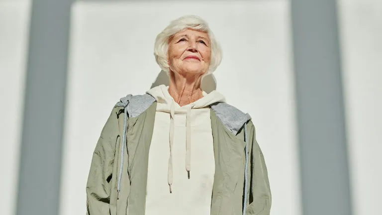 A confident older woman standing in sunlight