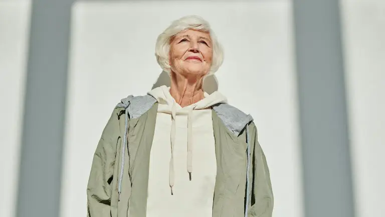 A confident older woman standing in sunlight
