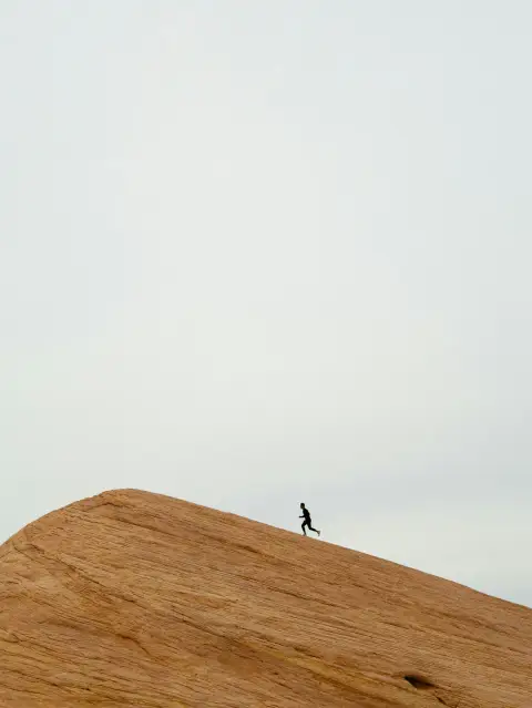 A runner crossing a sunlit ridge