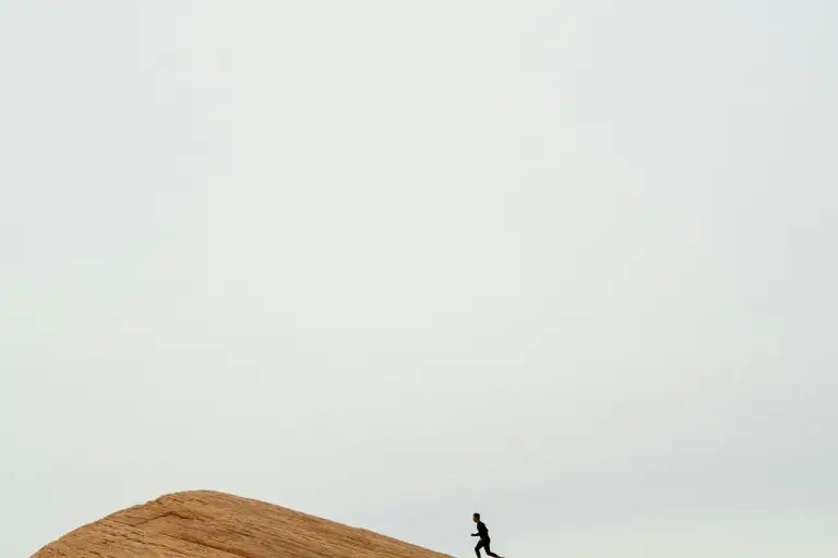 A runner crossing a sunlit ridge