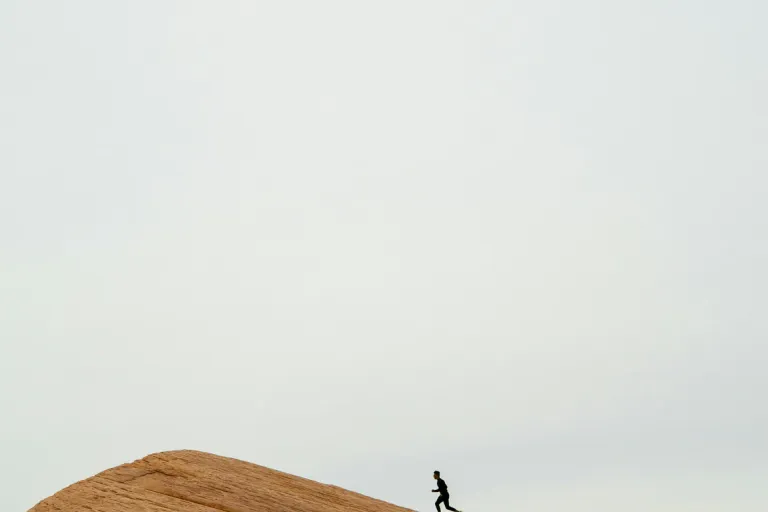 A runner crossing a sunlit ridge