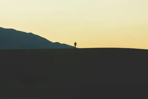 Silhouette of a hiker standing on a desert ridge at dusk