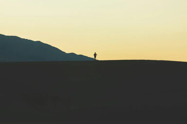 Silhouette of a hiker standing on a desert ridge at dusk