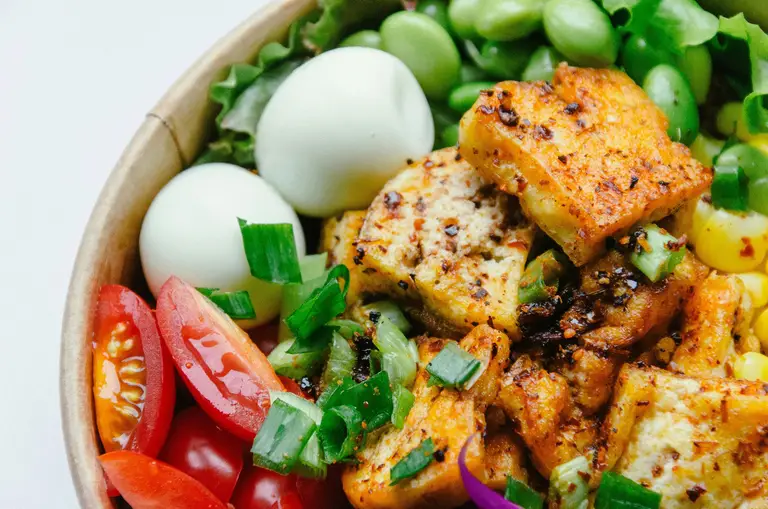 A colorful bowl of tofu, eggs, edamame, and fresh vegetables rich in phytoestrogens to support estrogen and progesterone levels during perimenopause.