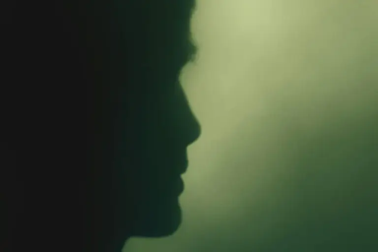 A face in profile against soft green light