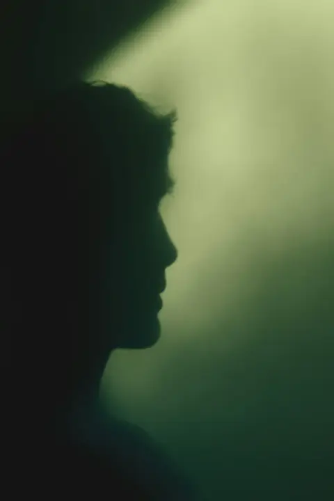 A face in profile against soft green light