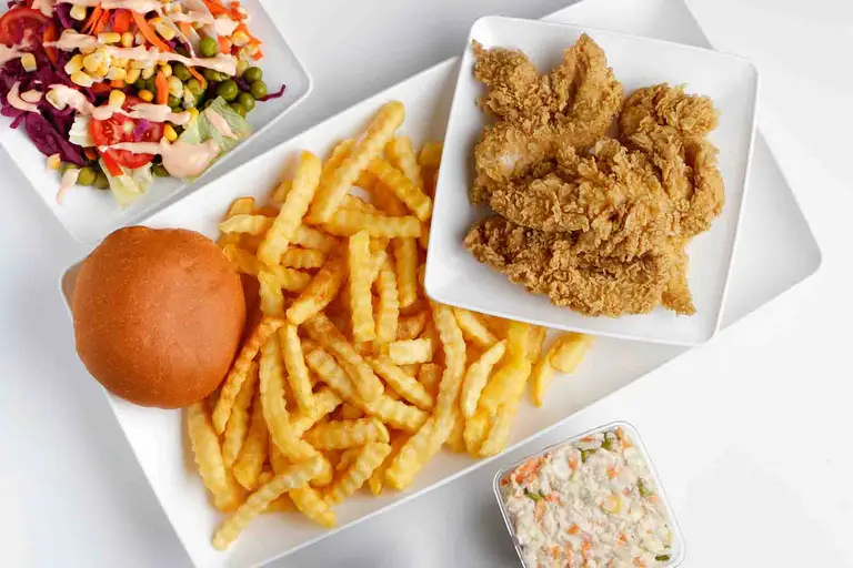 A plate featuring fried chicken, french fries, and coleslaw, demonstrating how a diet high in processed foods can contribute to declining testosterone levels.