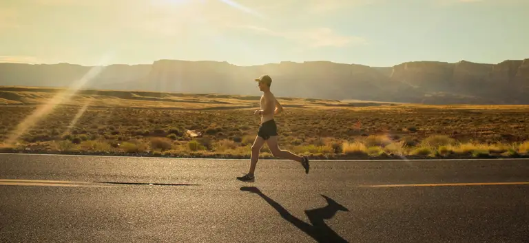 runner on a desert road at sunrise