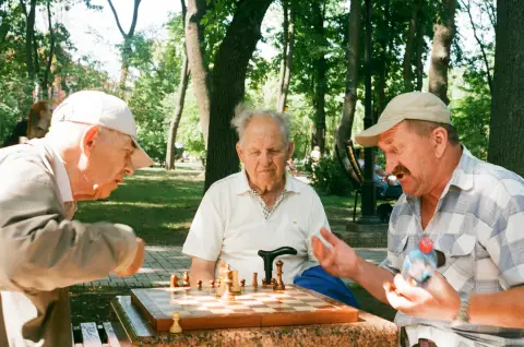 Two older adults playing chess outdoors
