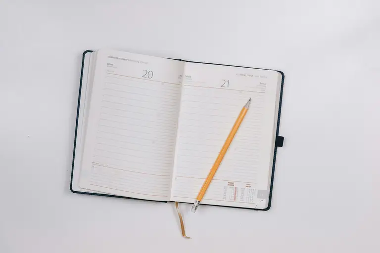 An open planner with blank lined pages and a pencil on top, symbolizing scheduling and planning for regular HbA1c tests and healthy lifestyle changes.