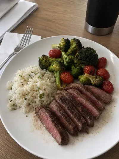 Plate of sliced steak, broccoli, cherry tomatoes, and rice