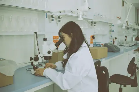 Scientist using a microscope at a laboratory workbench