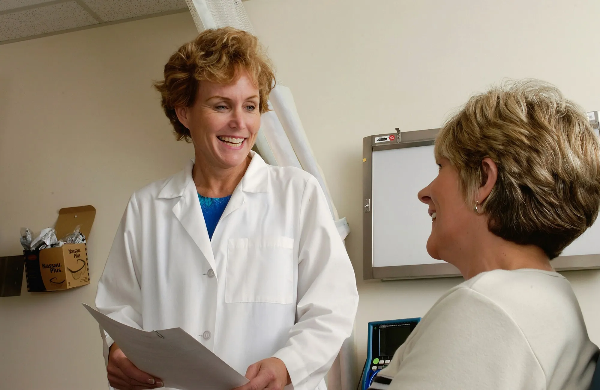 A middle-aged woman consulting with a female doctor about perimenopause symptoms, discussing estradiol and progesterone levels for hormone therapy.