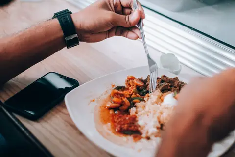 Person eating a balanced meal of rice and vegetables during an intermittent fasting eating window